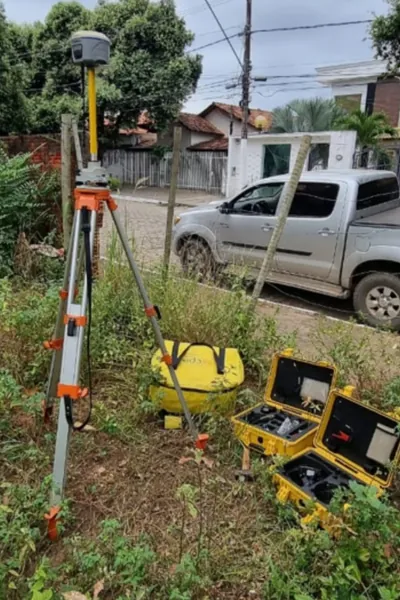 Receptor GNSS RTK montado em bastão no campo, ao lado da maleta do equipamento